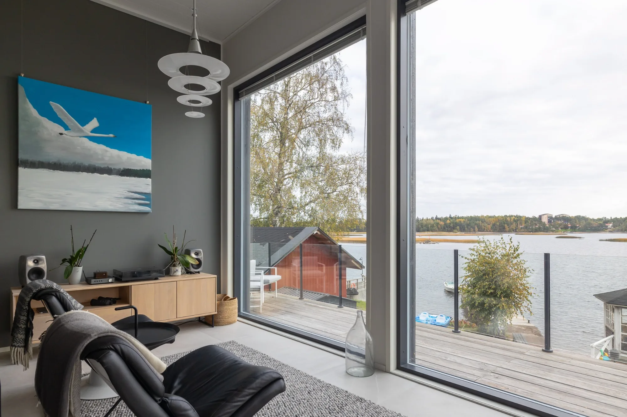 Olohuoneen yksityiskohta suurten ikkunoiden ja vesistön äärellä