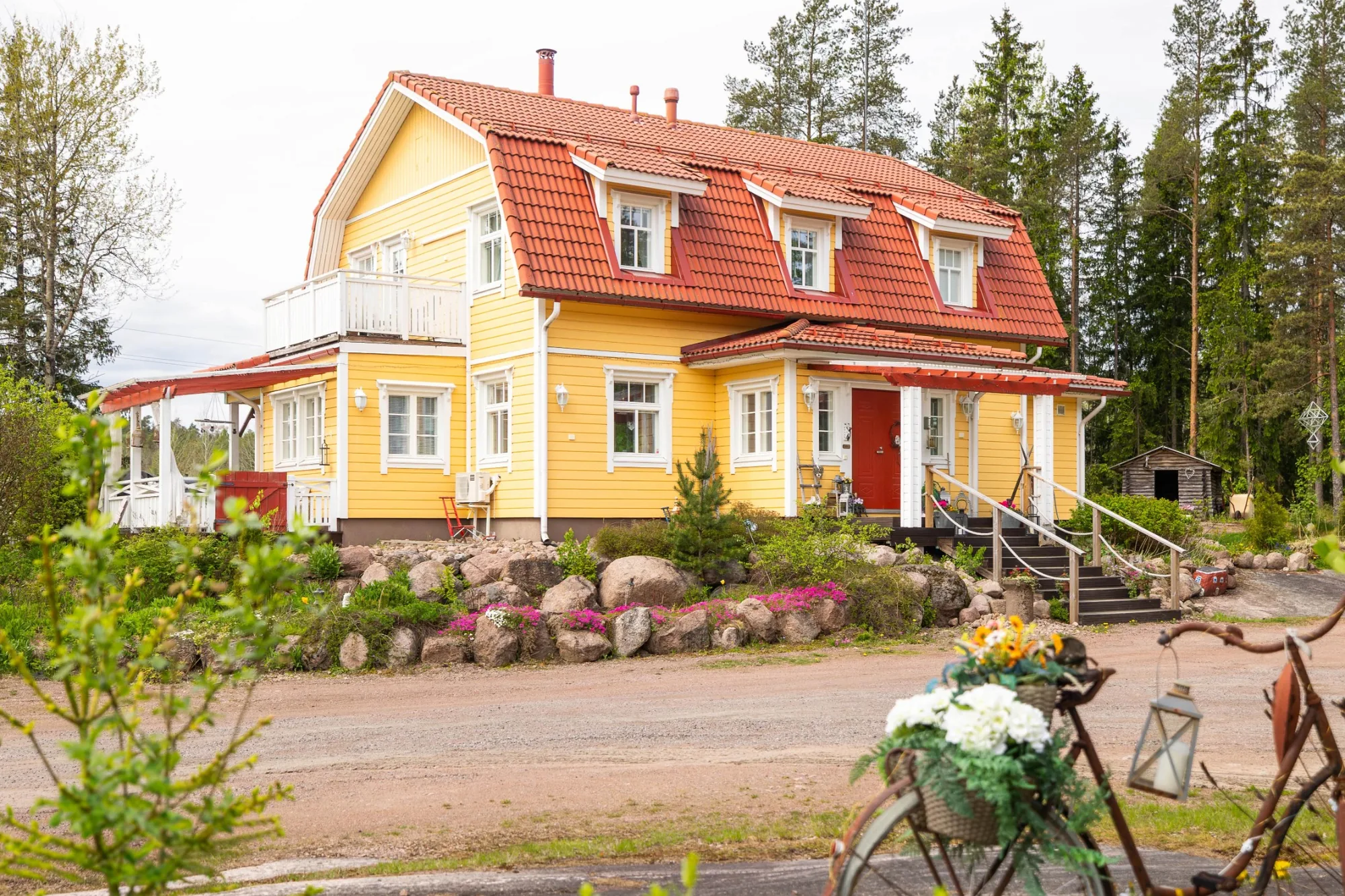 Keltainen puutalo ja vehreä pihapiiri